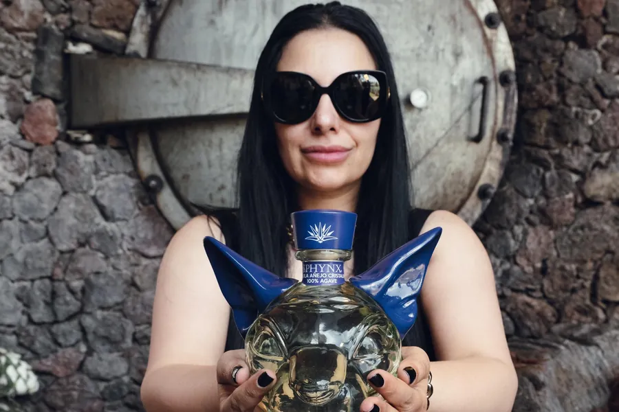 Sukhvinder Javeed in big black sunglasses, holding the SPHYNX Cristalino decanter