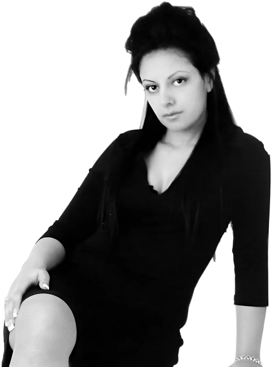 Sukhvinder Javeed in a black dress, seated, looking straight into the camera